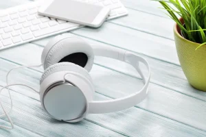 Fones de ouvido brancos, teclado e planta. Problemas comuns em fones TWS.